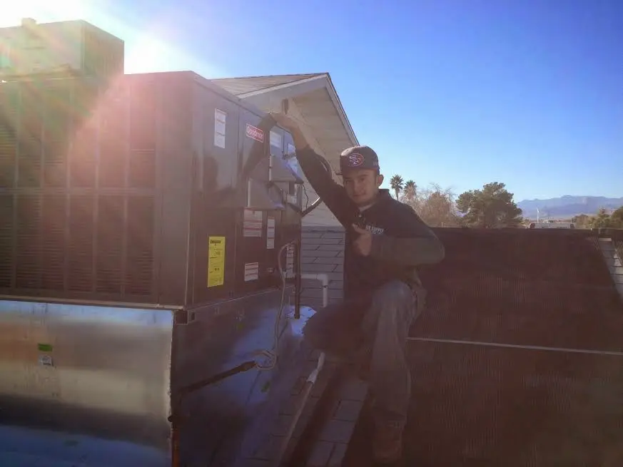 HVAC technician performing AC Tune-Up on a rooftop unit in Thomaston